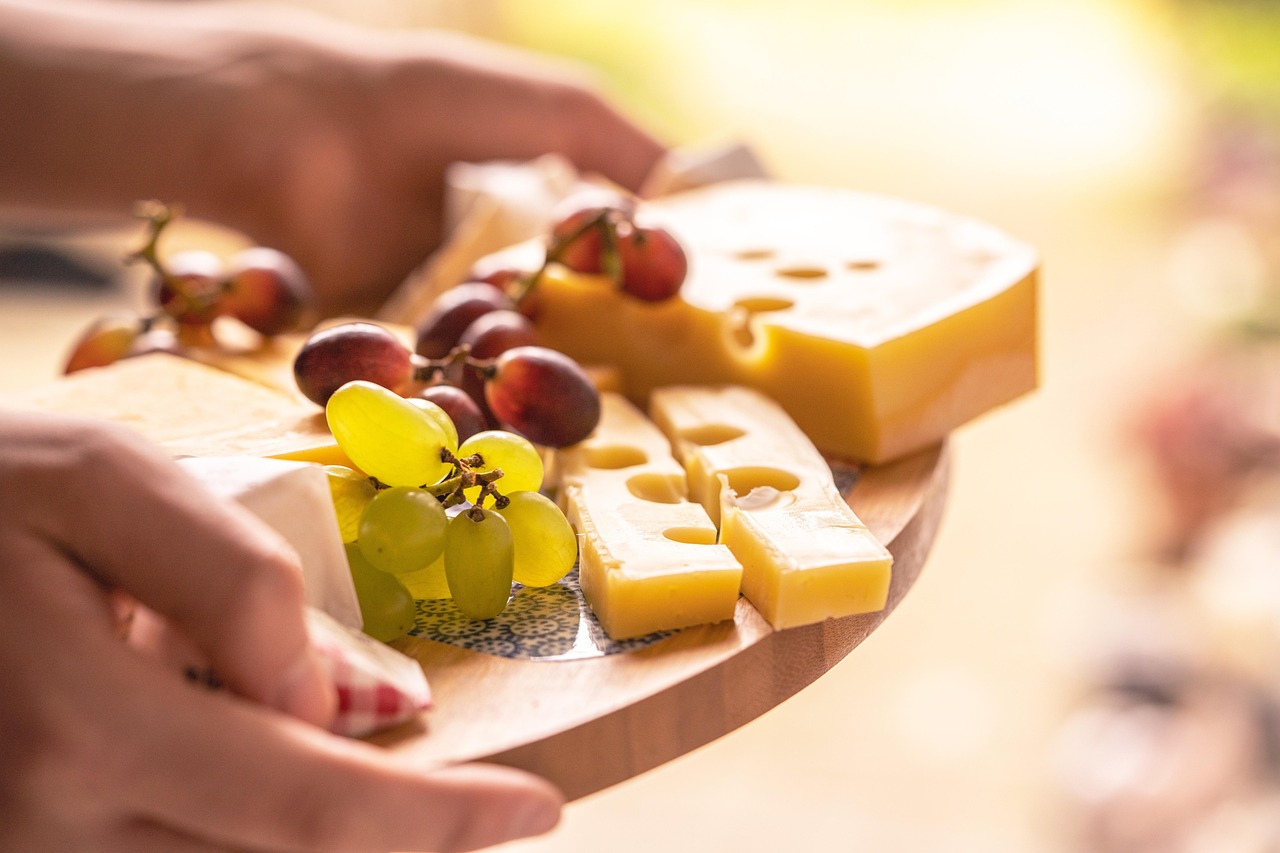 Porzione di formaggio su un tagliere con frutta e noci, simbolo di una dieta equilibrata.