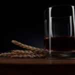 Bottiglia di amaro fatto in casa con erbe e spezie sul tavolo di legno.