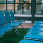 Viaggiatore sdraiato su una panchina in aeroporto, circondato da bagagli, mentre dorme tranquillamente.