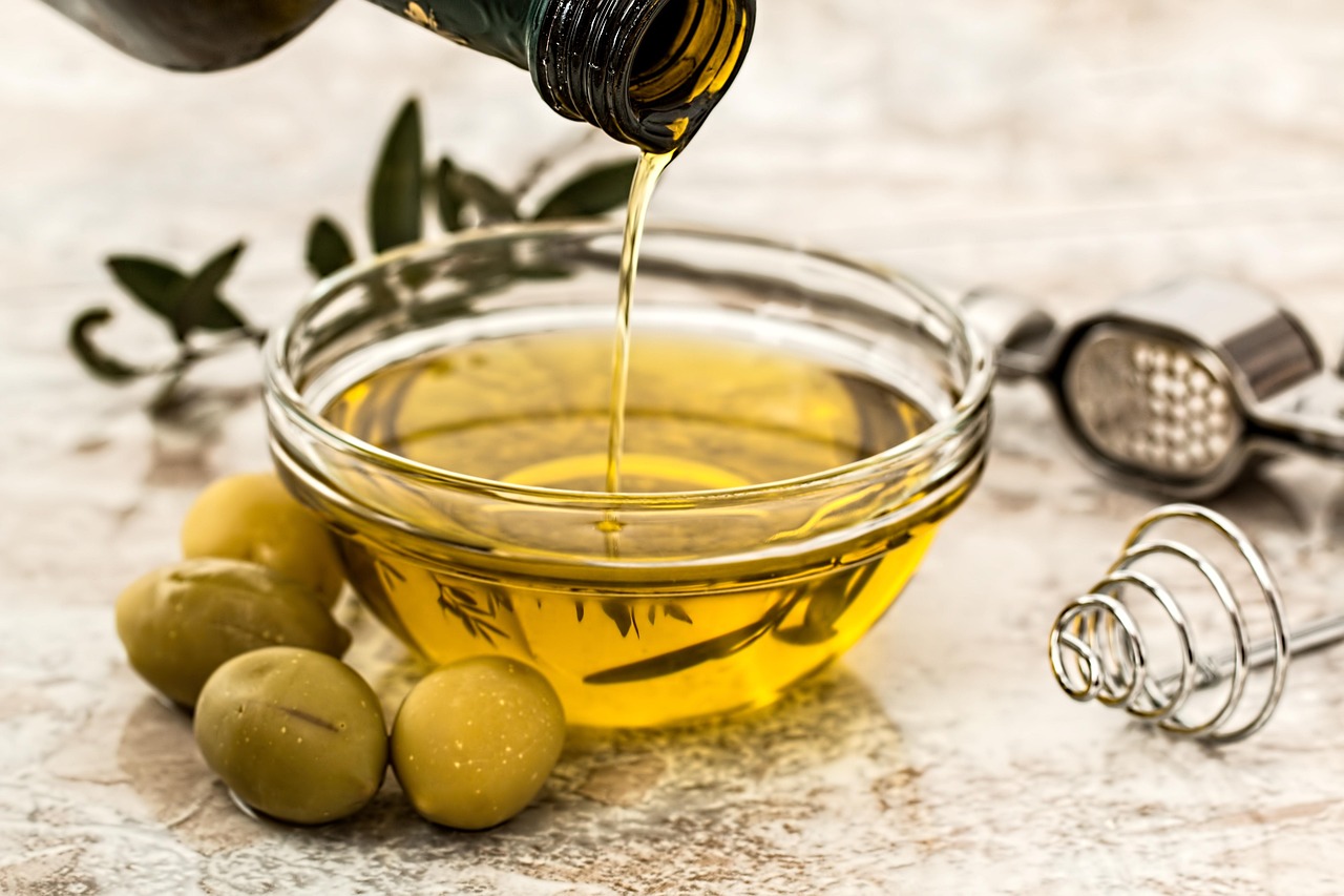 Bottiglia di olio vegetale con etichetta "miglior olio per colesterolo" su sfondo neutro.