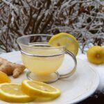 Bicchiere di acqua con limone e zenzero fresco, ingredienti per accelerare il metabolismo.