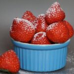 Fragole fresche su un tavolo, simbolo di rimedio naturale per il gonfiore addominale.