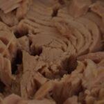 Immagine di diverse scatole di tonno scaduto con etichette di marche da evitare.