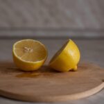 Fetta di limone immersa in un bicchiere di acqua calda su un tavolo di legno.