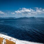 Vista panoramica di una crociera nel Mediterraneo con navi e isole sullo sfondo.